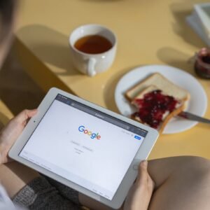 Person using a tablet with Google search open while having breakfast with toast and tea.