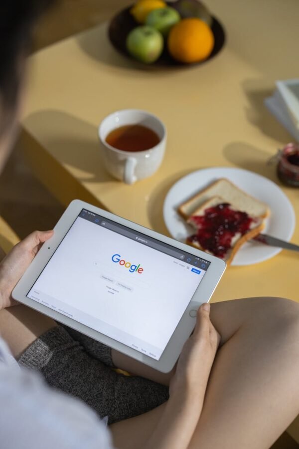 Person using a tablet with Google search open while having breakfast with toast and tea.